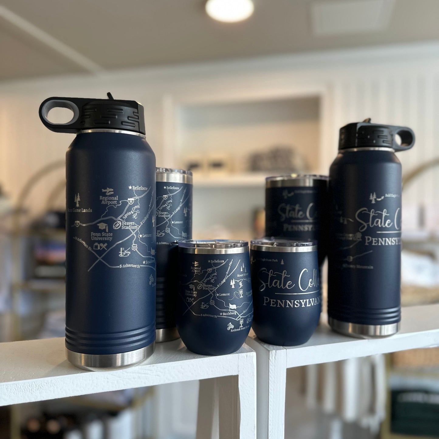 Set of navy blue insulated tumblers with silver bases on a white shelf.