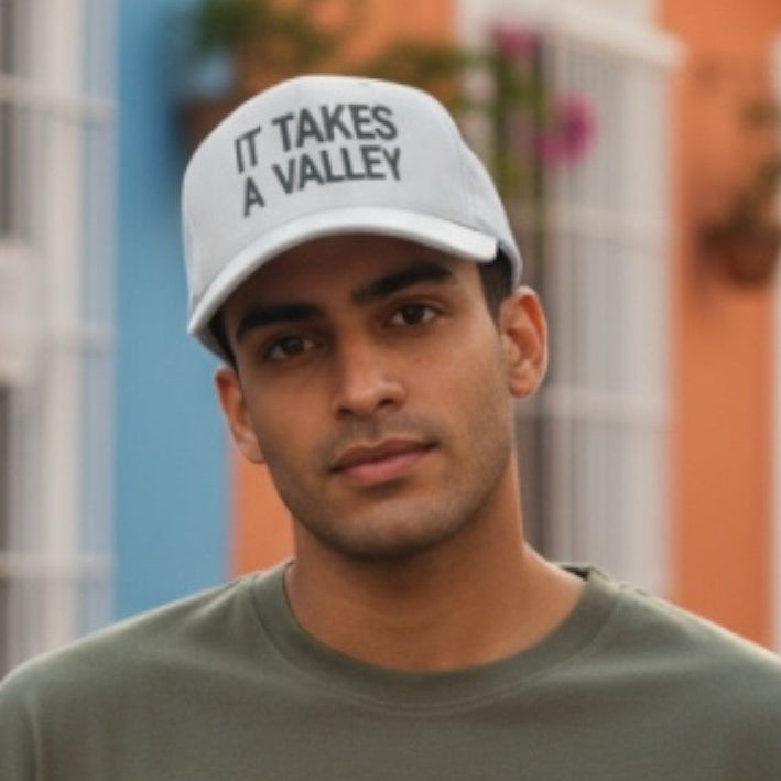 Man wearing a cap with text in front of colorful buildings