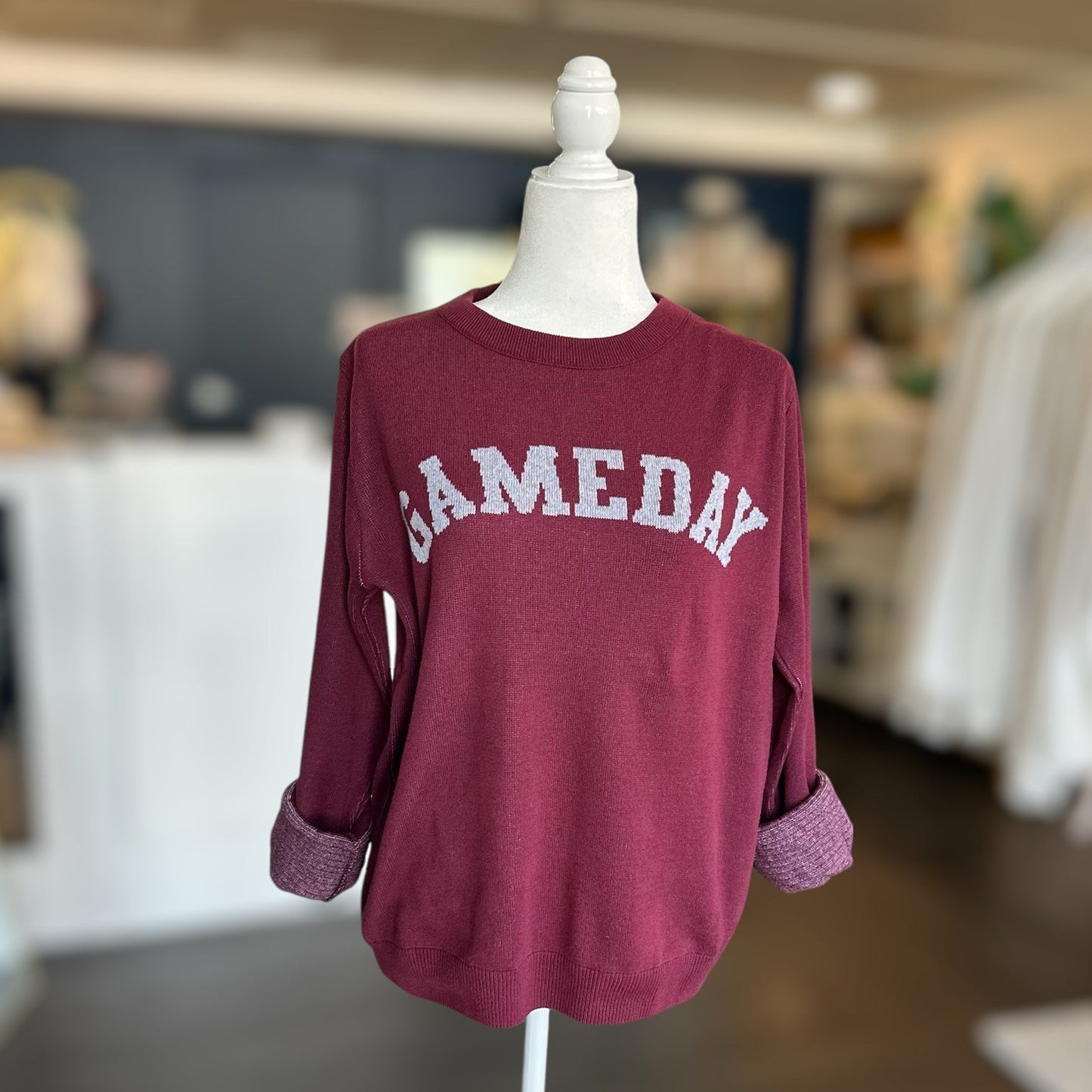 Maroon sweatshirt with 'SAMEDAY' text on a mannequin in a store setting