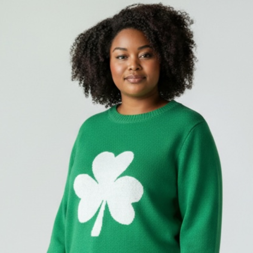 Person wearing a green sweater with a white shamrock design on a plain background