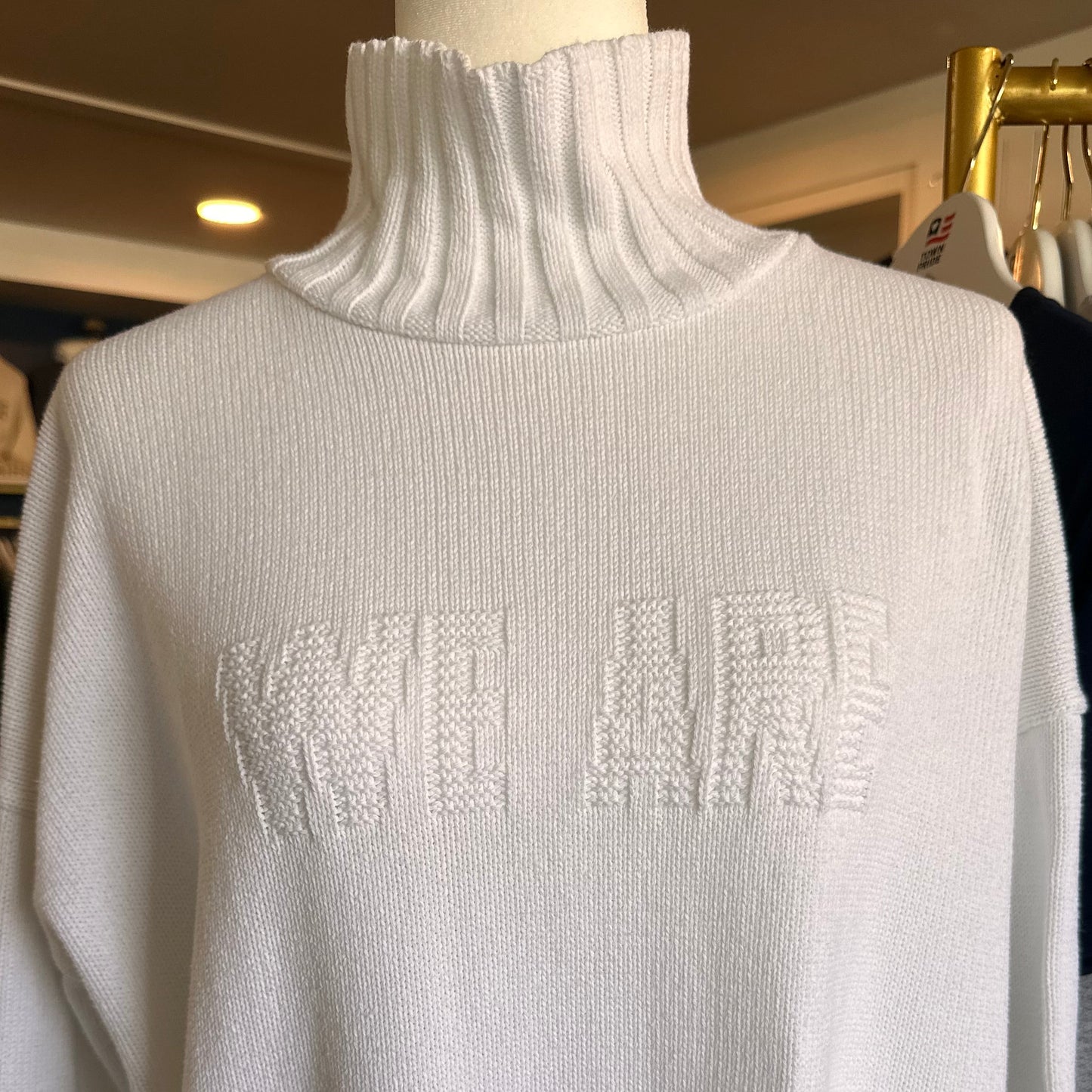 White sweater with brand logo on a rack