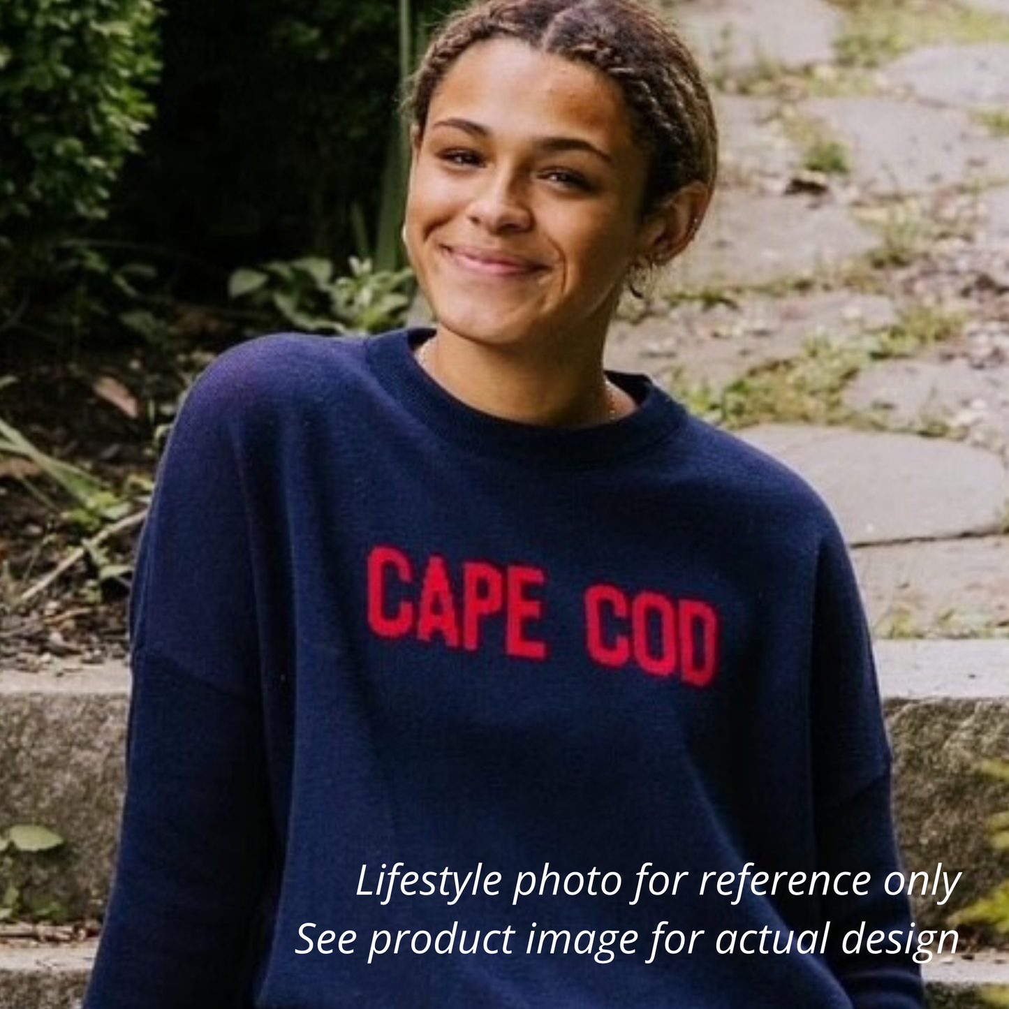 Person wearing a navy blue sweater with 'CAPE COD' in red text, standing outdoors.