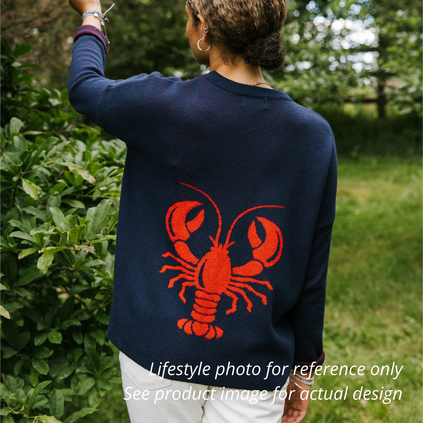 Person wearing a navy sweater with a red lobster design outdoors