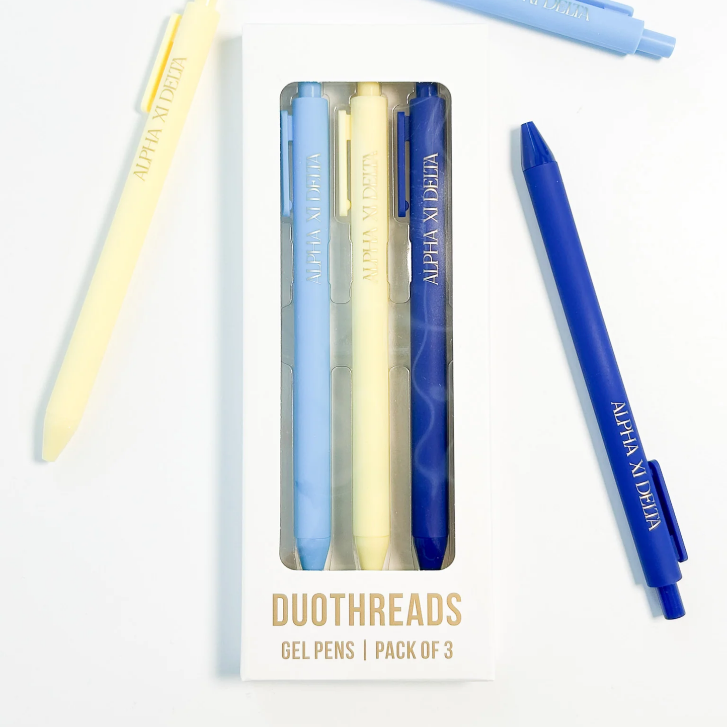 Set of three gel pens in blue, yellow, and clear packaging with 'Alpha Xi Delta' branding on a white background.