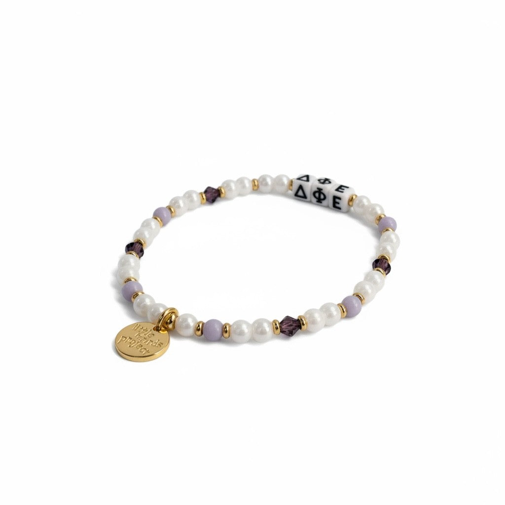 Bracelet with pearls, gold charm, and purple beads on a white background