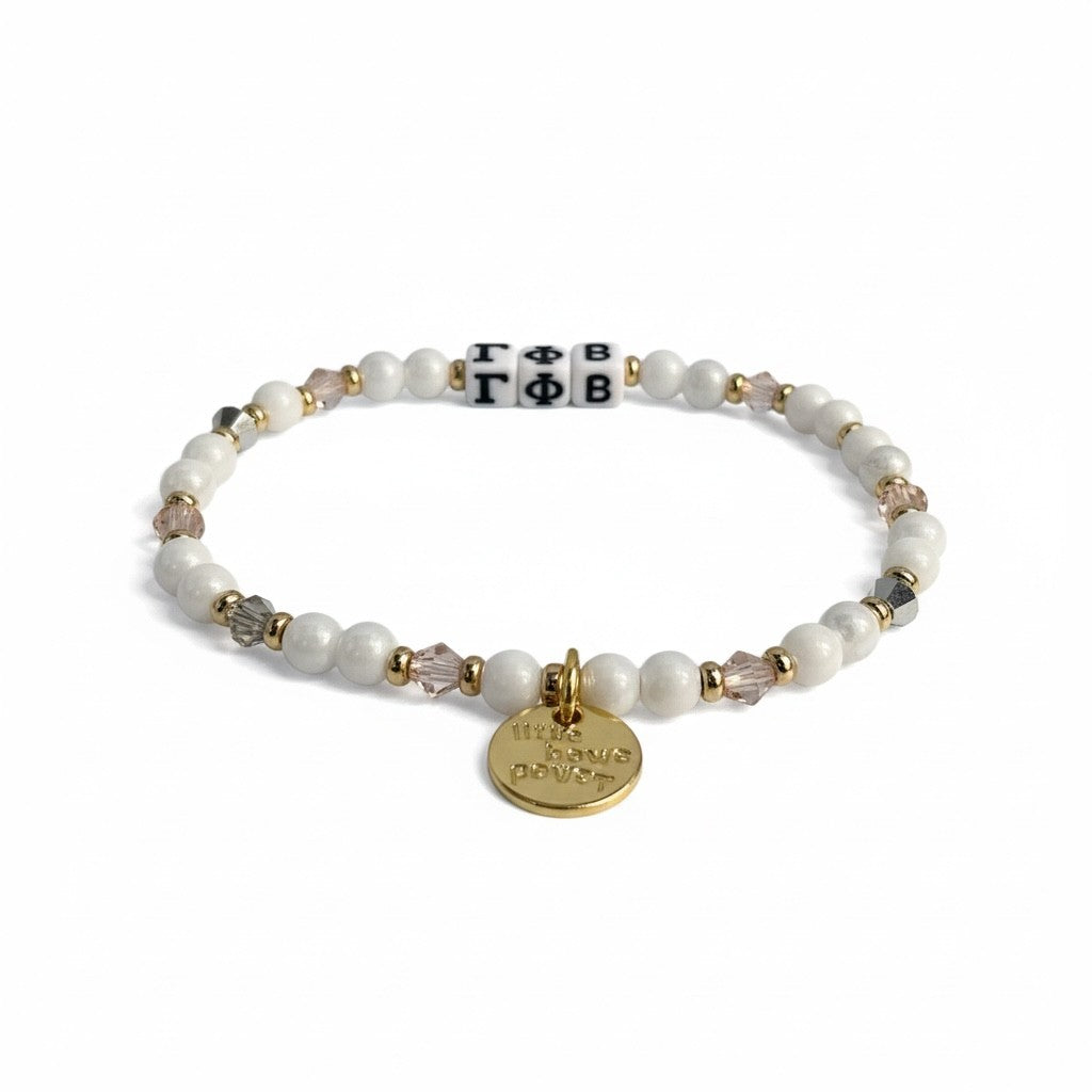 Bracelet with pearls, crystals, and a gold tag on a white background