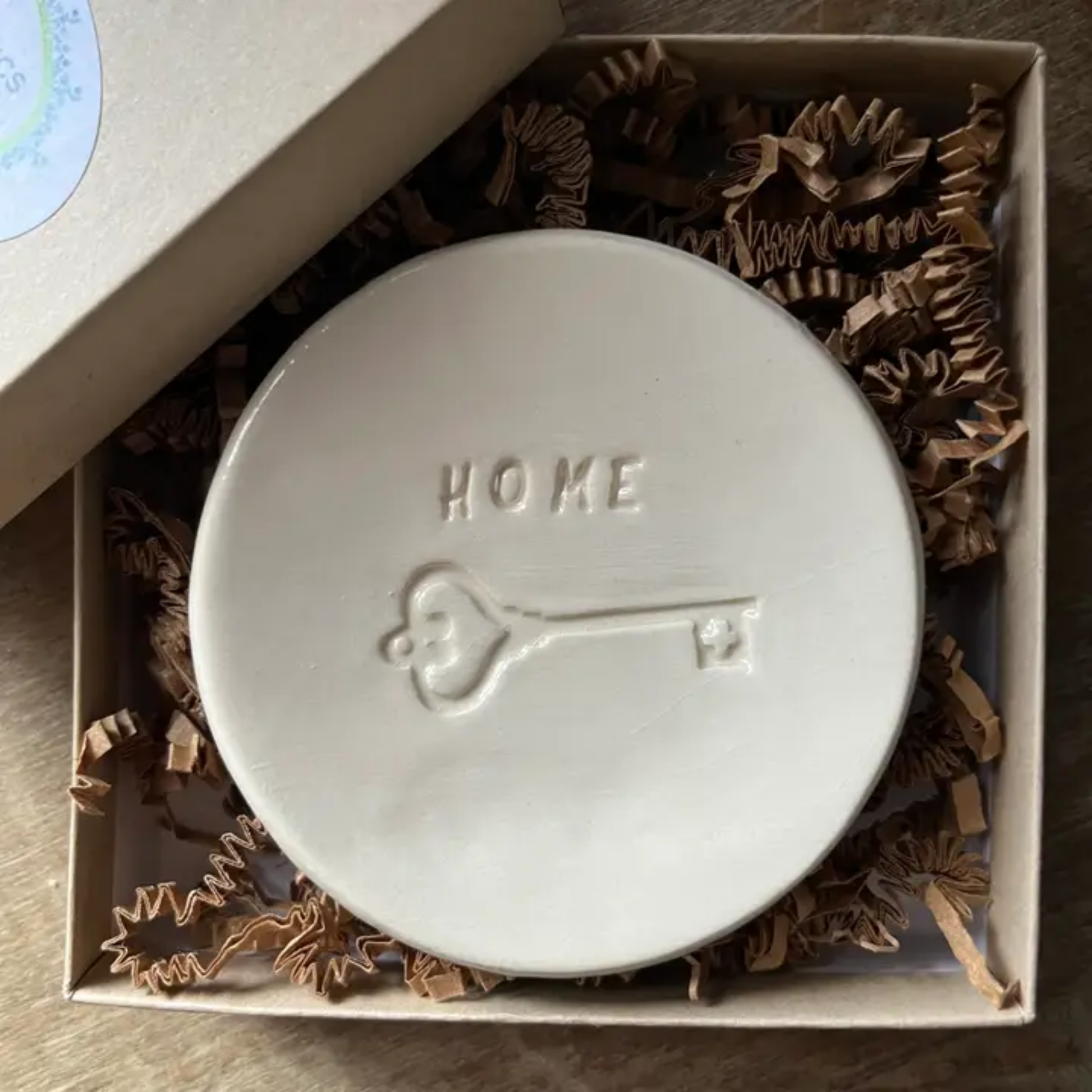 Round ceramic dish with 'HOME' and key embossing in a box with decorative paper