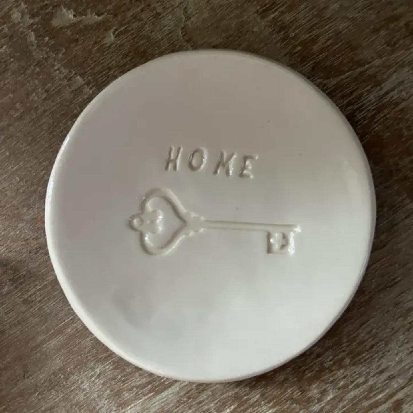 White ceramic dish with 'HOME' and a heart key design on a wooden surface