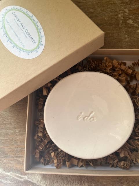 Round beige product in a brown box with a visible brand logo on a wooden surface