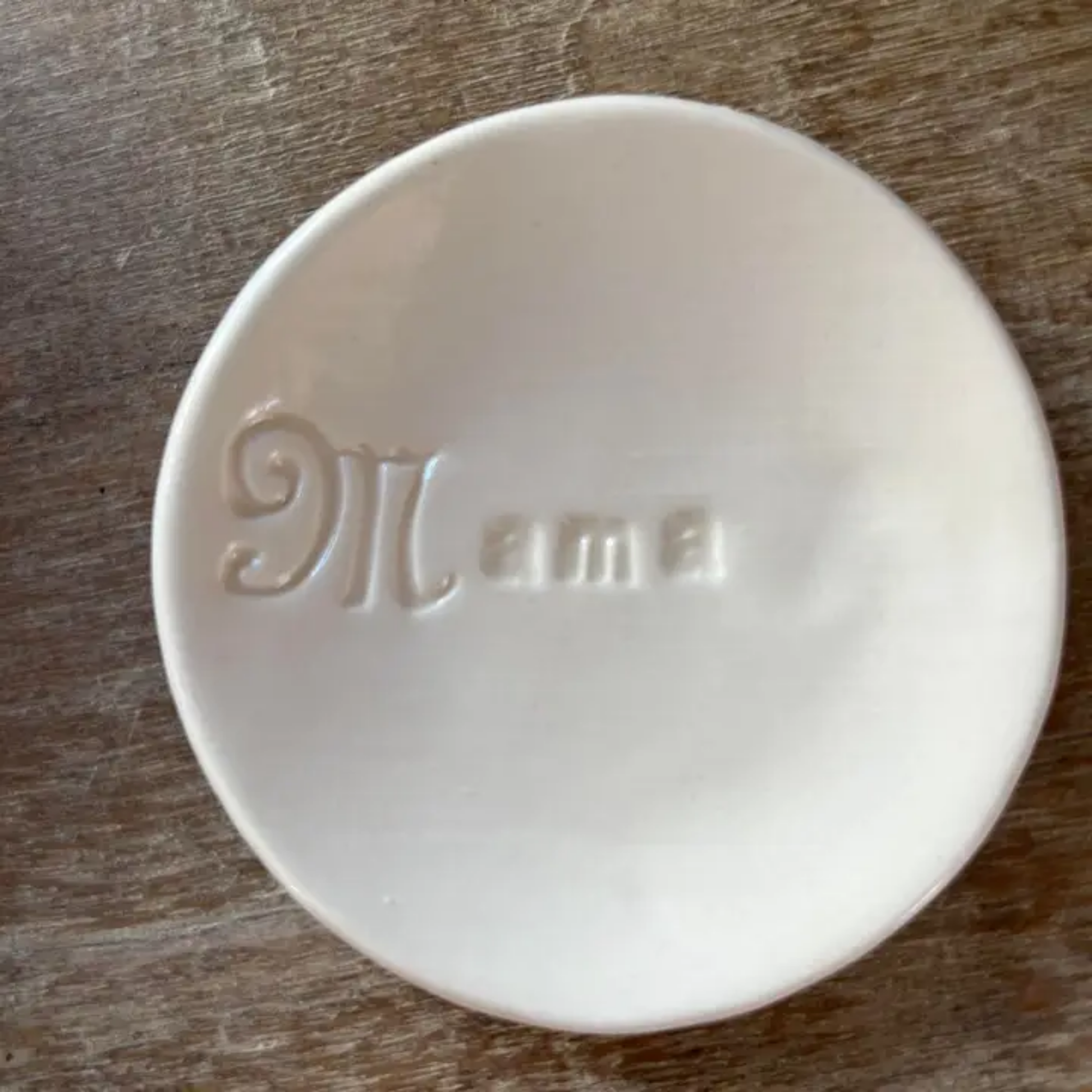White ceramic bowl with 'Mama' engraving on a wooden surface