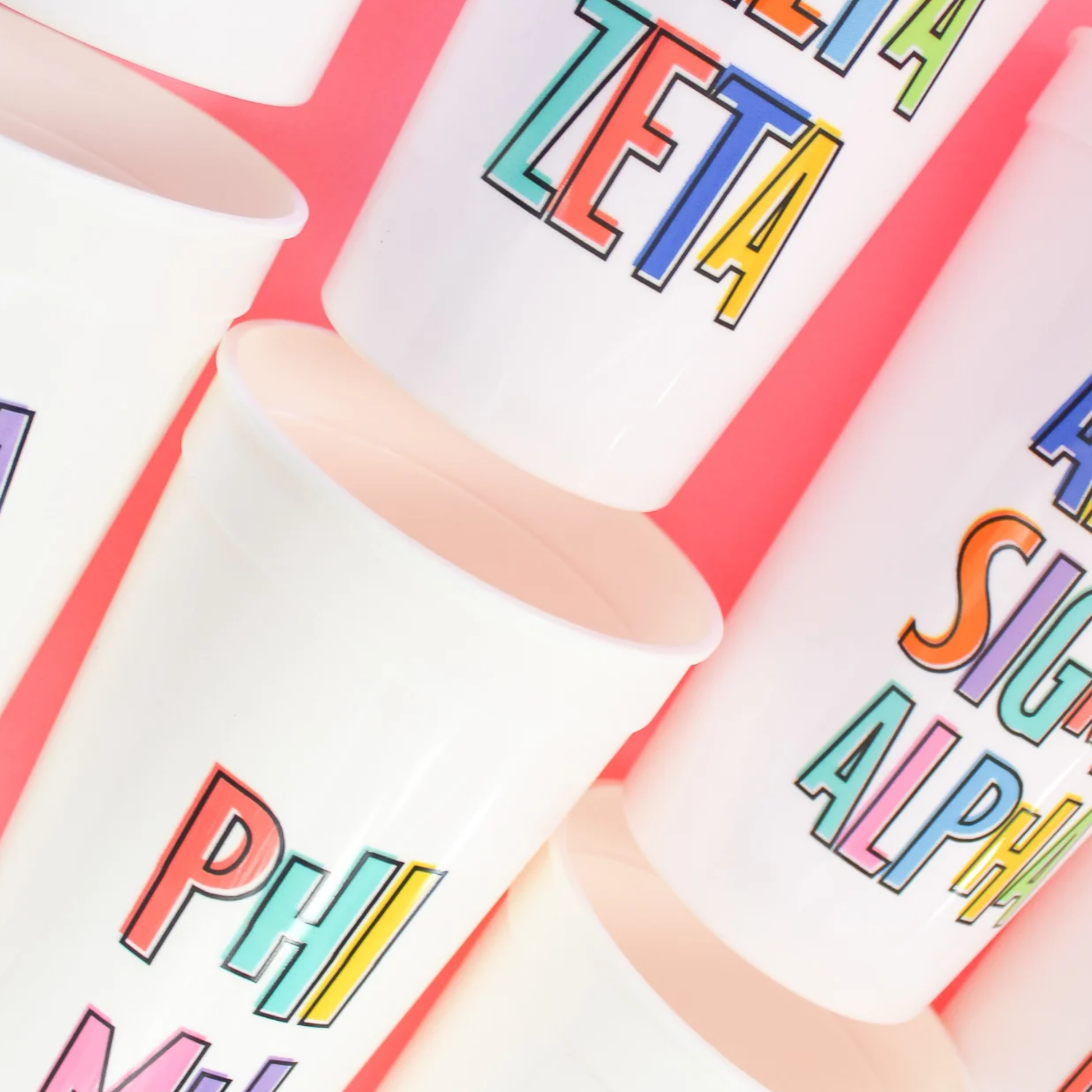 Colorful letters on white cups against a red background