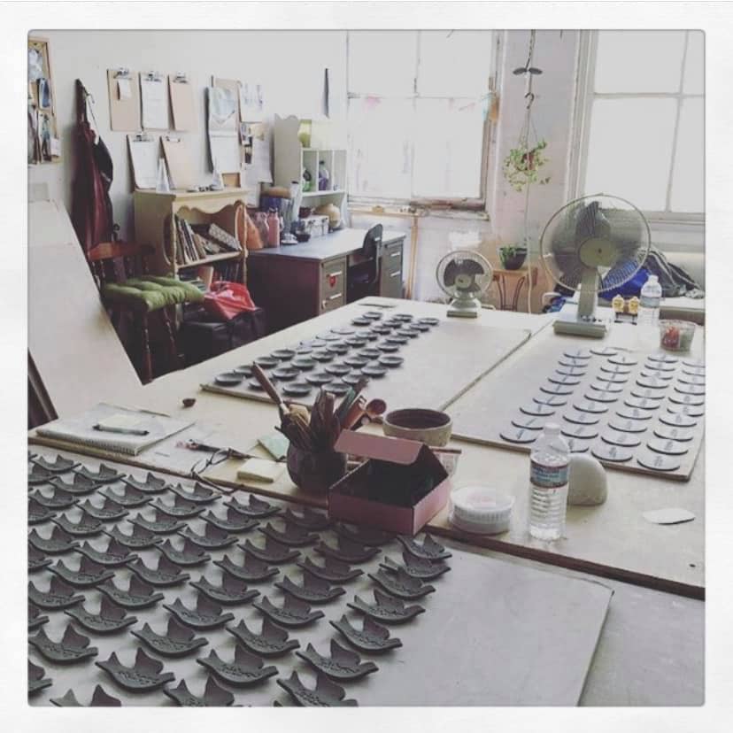 Workshop or studio with tables displaying ceramic pieces and office supplies.