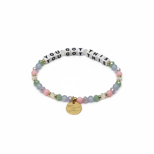 Bracelet with pastel beads and a gold tag on a white background