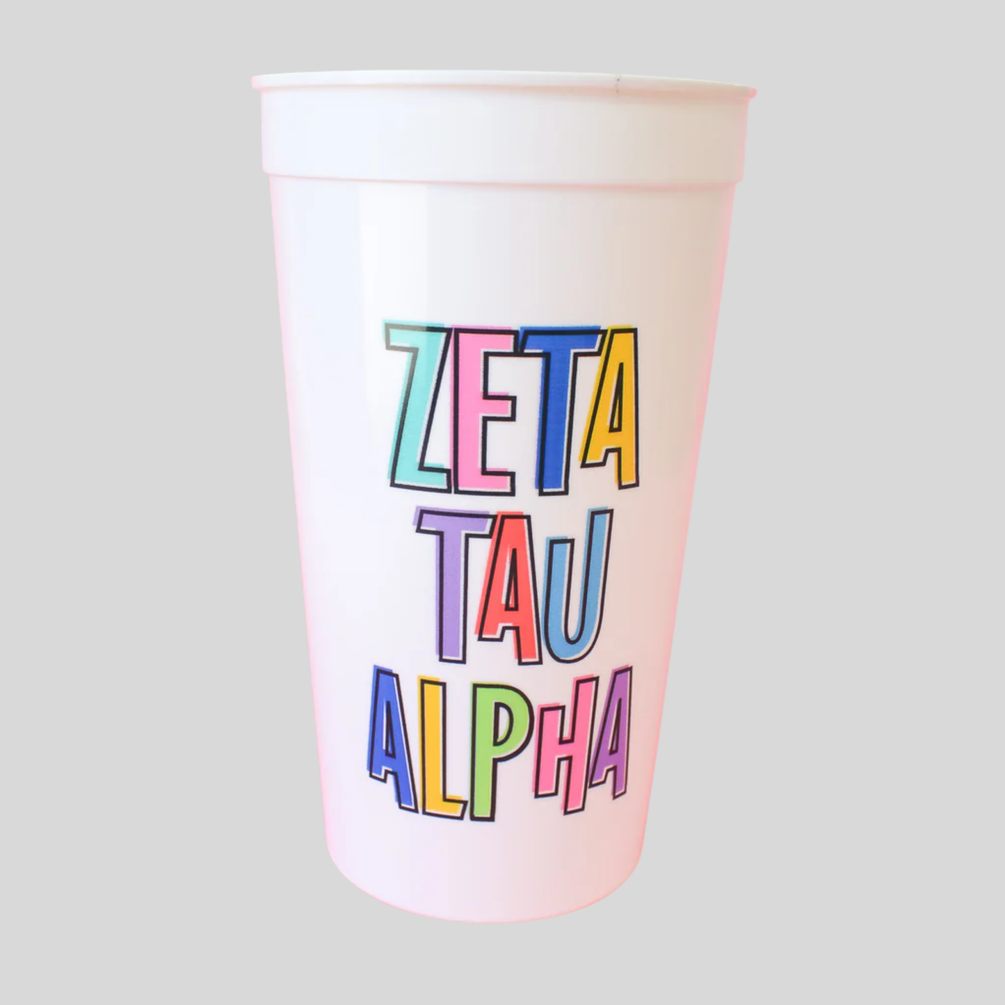 Colorful 'Zeta Tau Alpha' text on a white cup against a light gray background