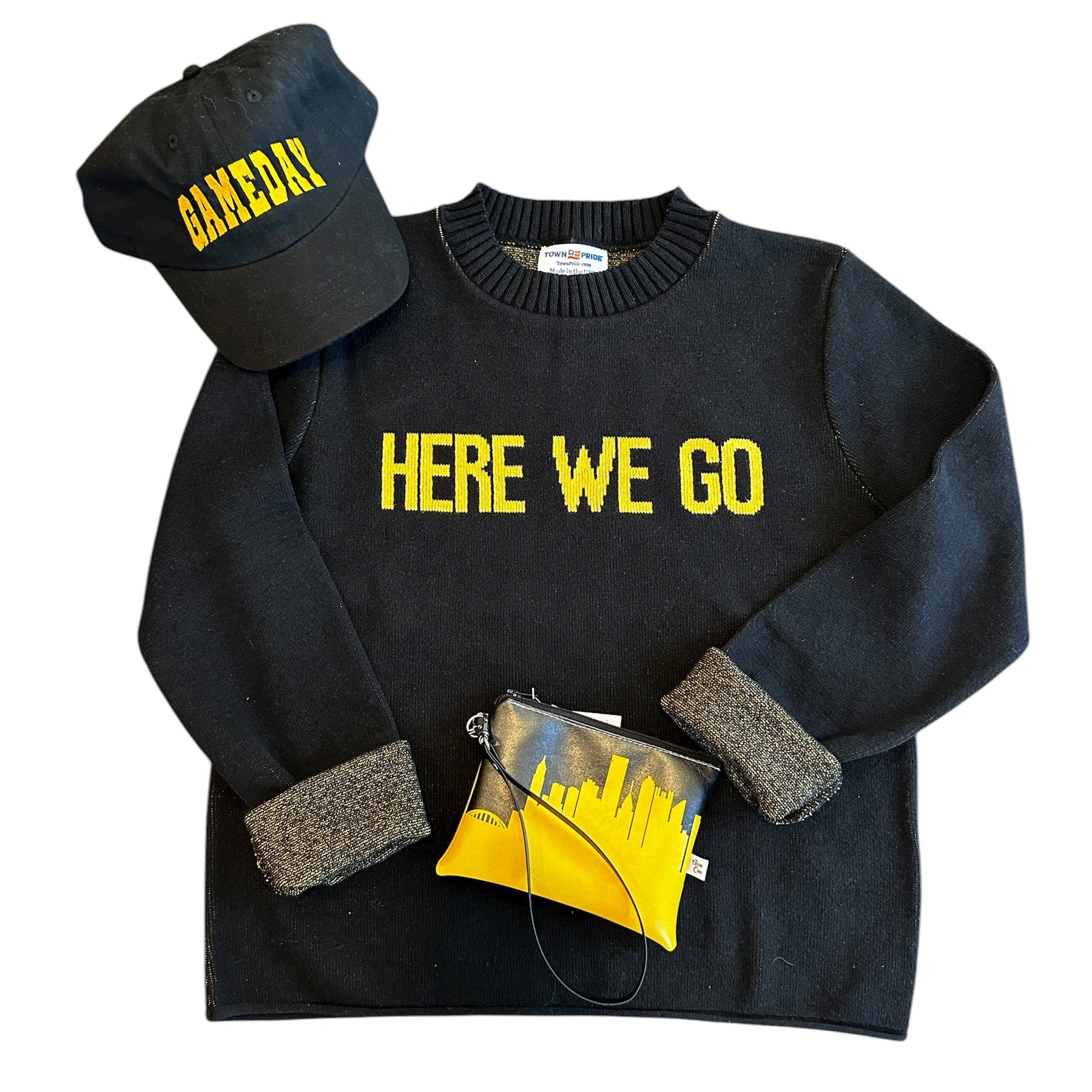 Black sweater with 'HERE WE GO' text, black cap with yellow text, yellow clutch bag on a white background