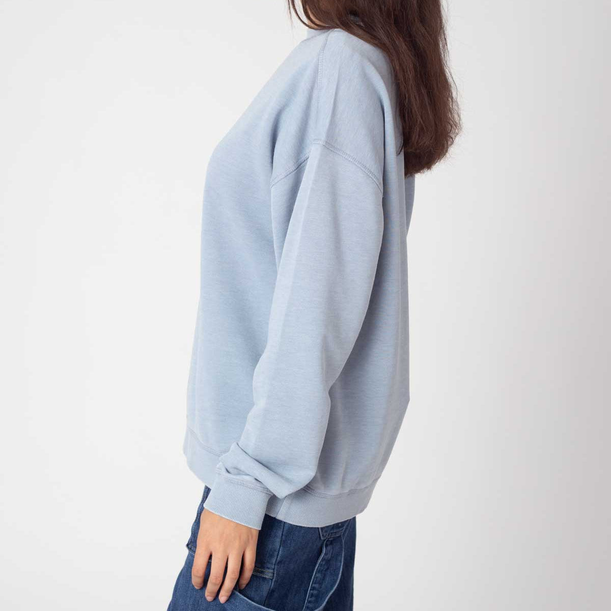 Woman wearing a light blue sweater and jeans on a white background
