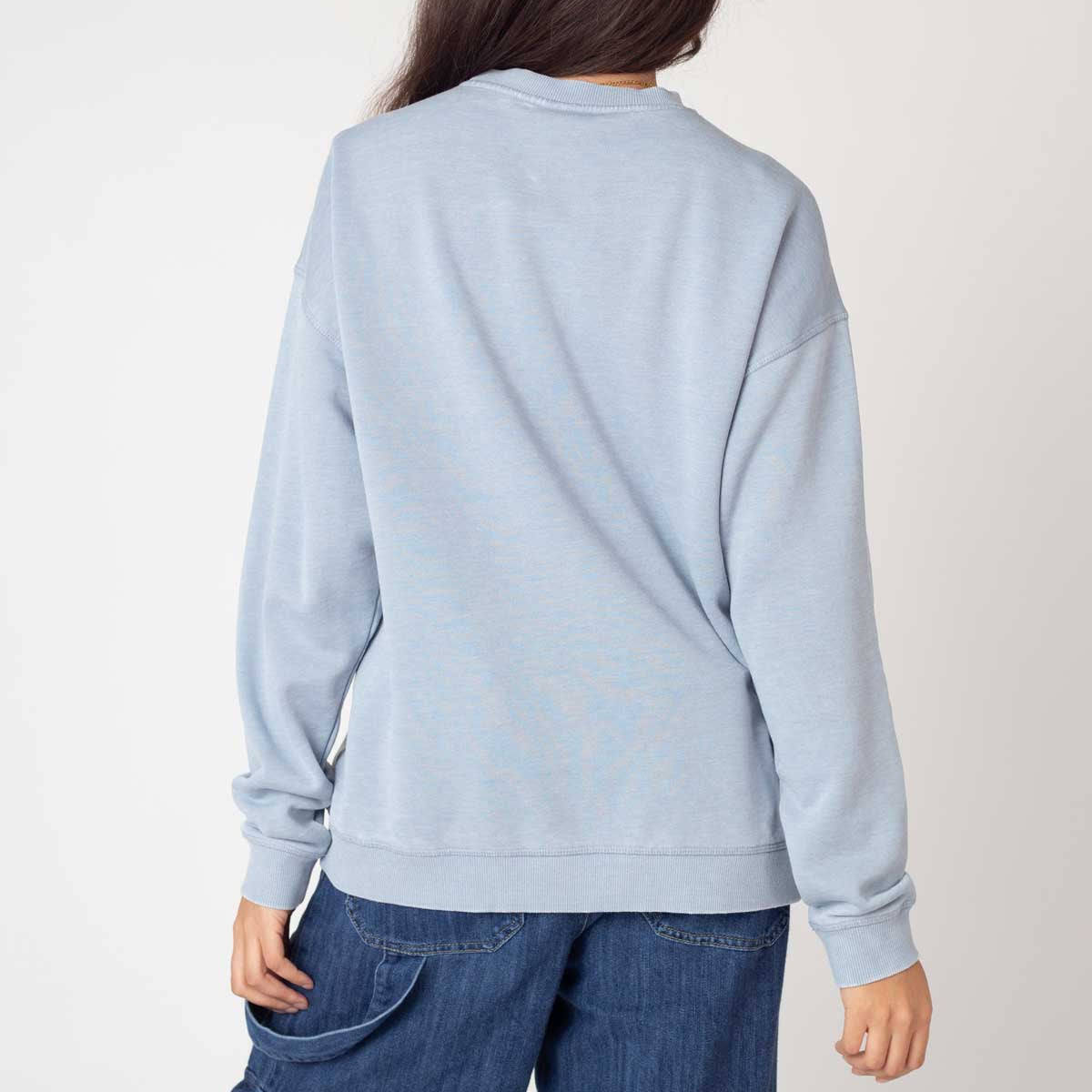 Person wearing a light blue sweatshirt and blue jeans on a plain background