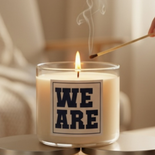 Candle with 'WE ARE' label being lit with a match