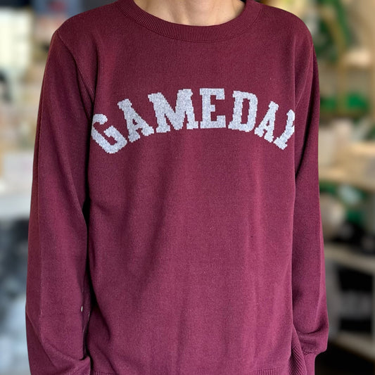 Person wearing a maroon sweater with 'GAMEDAY' text in a casual setting
