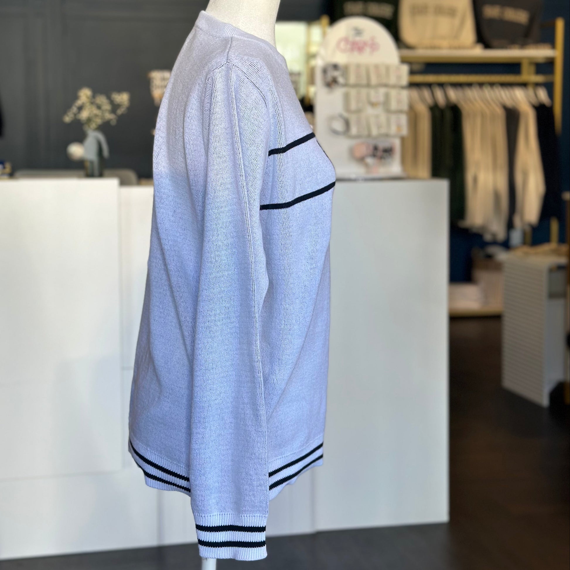 Light blue sweater with dark trim on a mannequin in a store setting