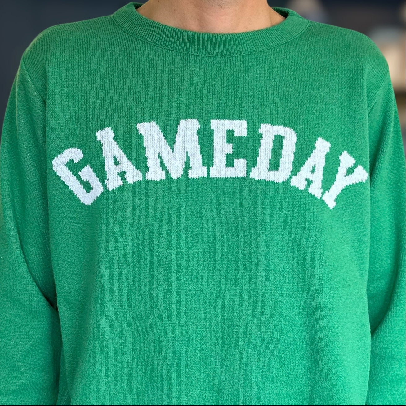 Green sweatshirt with 'GAMEDAY' text in white on a blurred background