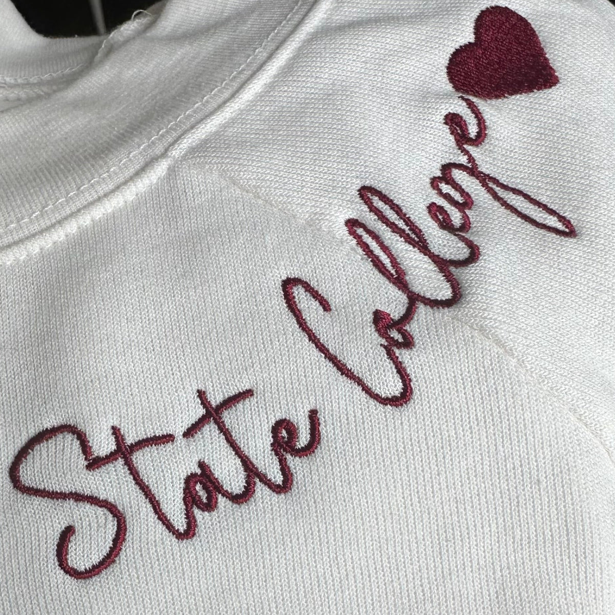 Embroidered text on a garment with a heart symbol