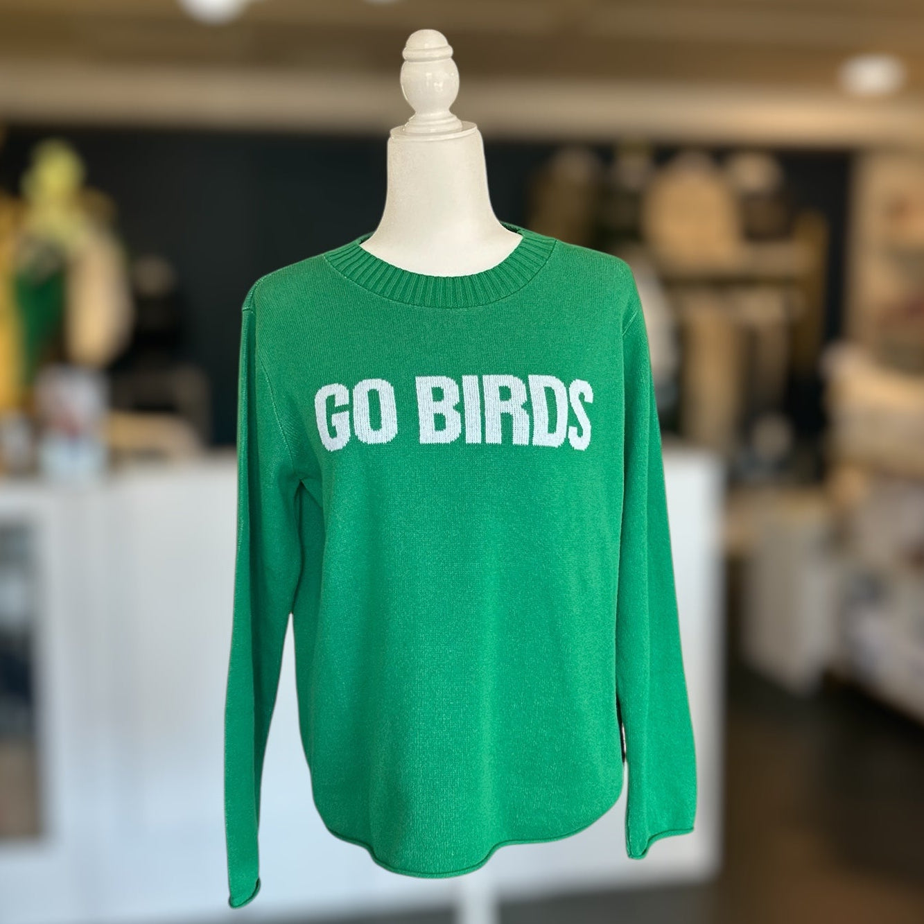 Green long-sleeve shirt with 'GO BIRDS' text on a mannequin in a store setting.