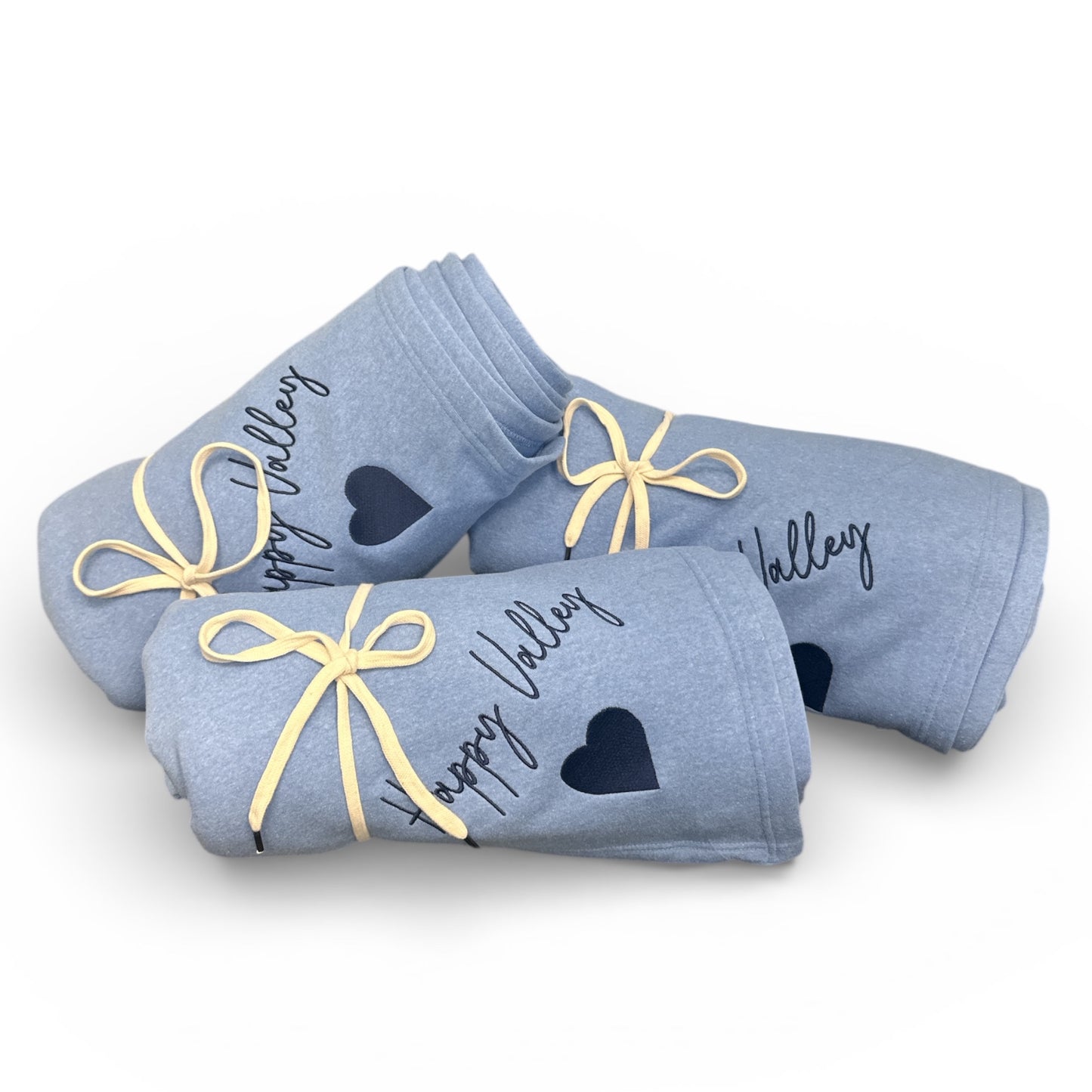 Three blue baby socks with heart designs and 'Happy Valley' text on a white background