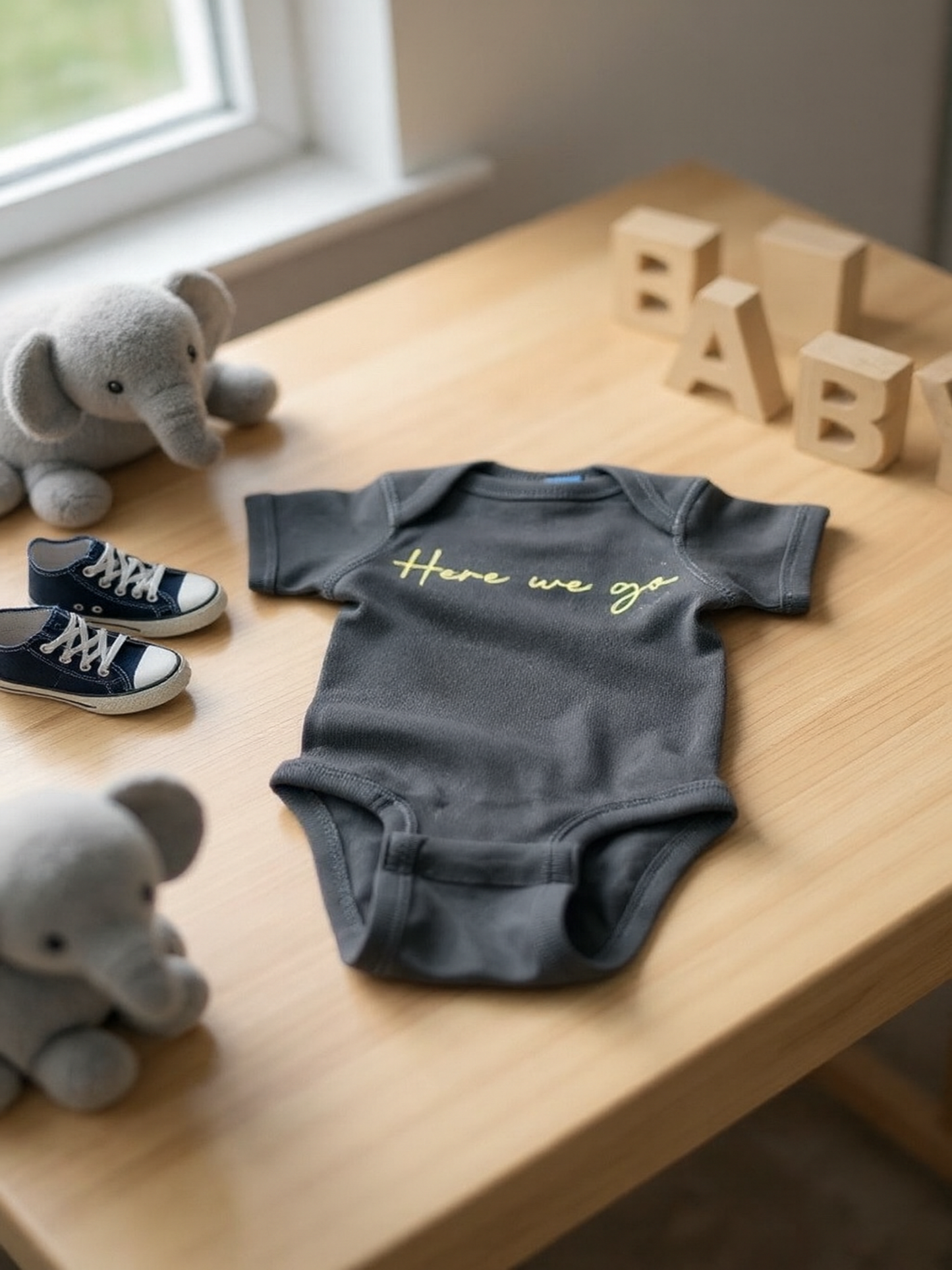 “Here We Go” black and gold baby onesie displayed in a cozy nursery – Town Pride infant apparel made with Rabbit Skins® quality.