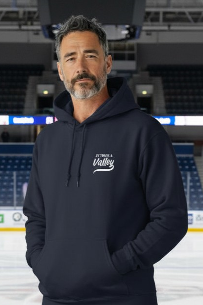 Man wearing navy hockey hoodie with It Takes a Valley script at an indoor ice rink