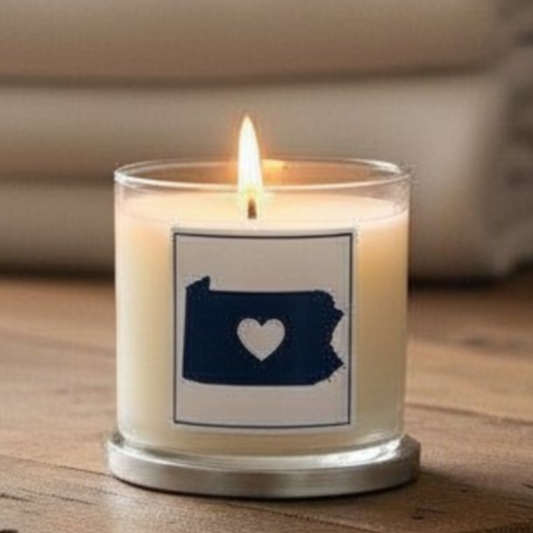 Candle with a Pennsylvania-shaped label featuring a heart on a wooden surface.