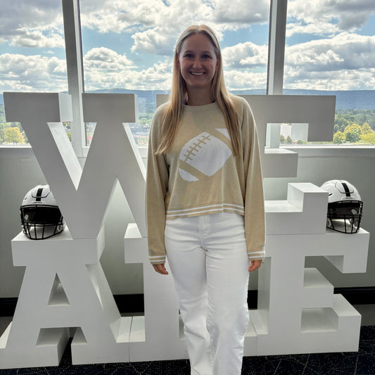 Person standing in front of large white letters spelling 'WE ARE' with a scenic background.