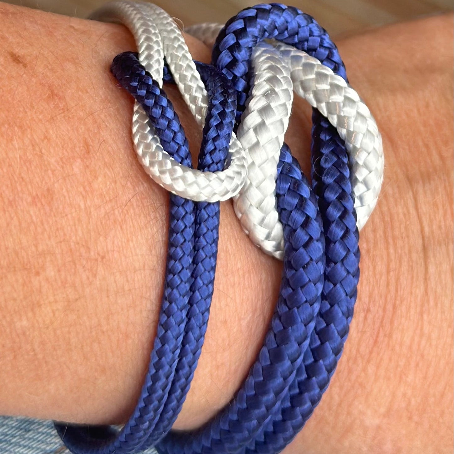 Close-up of a wrist wearing a blue and white braided bracelet.