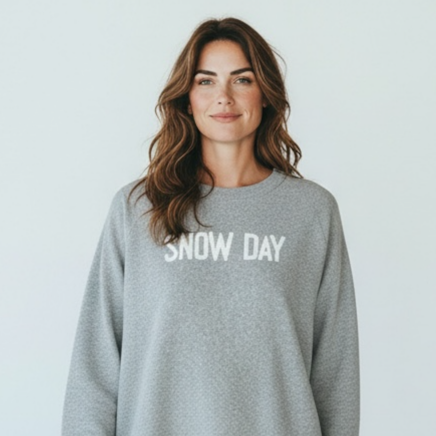 Woman wearing a gray sweatshirt with 'SNOW DAY' text on a light background