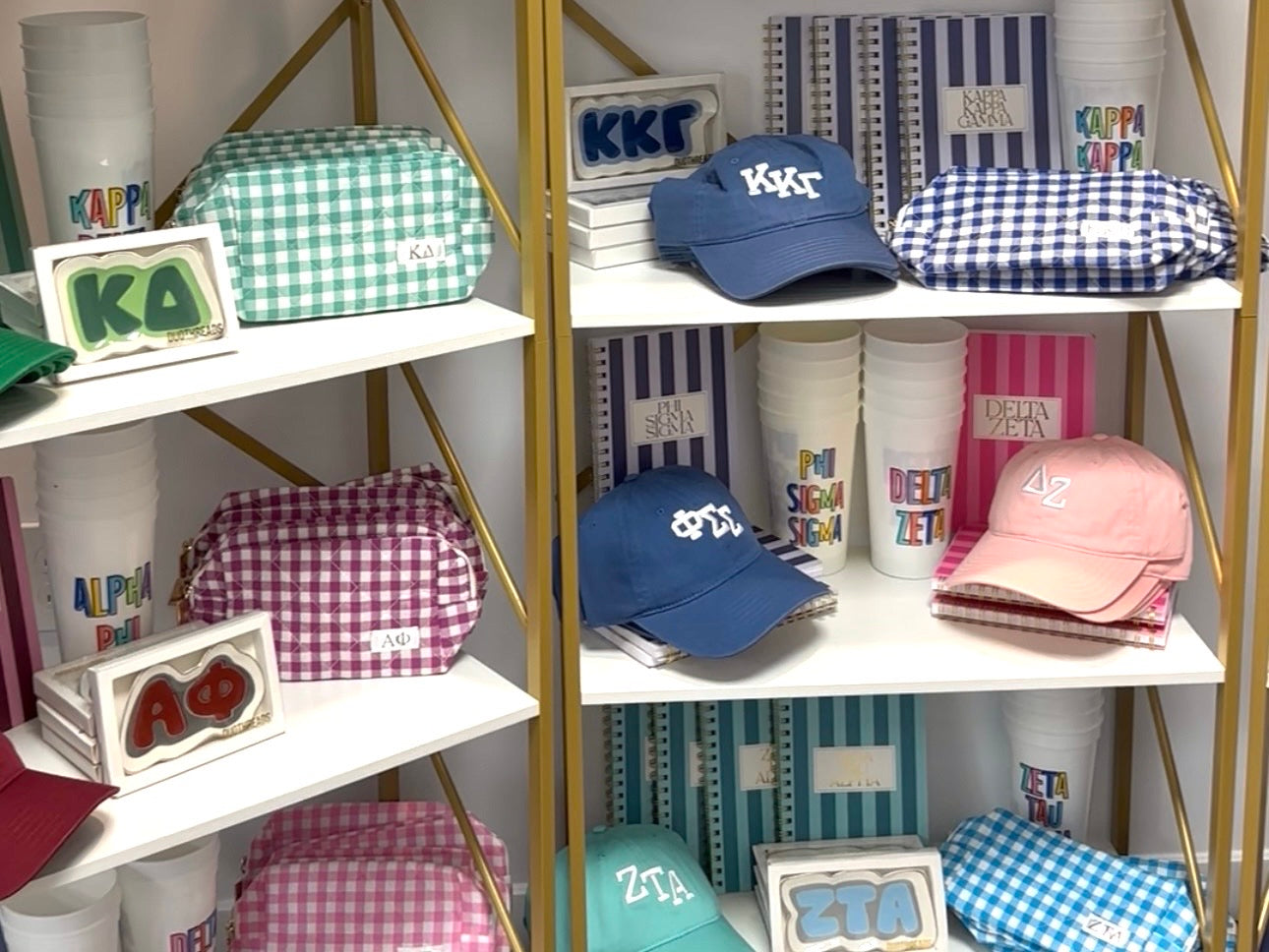 Shelves displaying various Greek letter merchandise including hats and tumblers.
