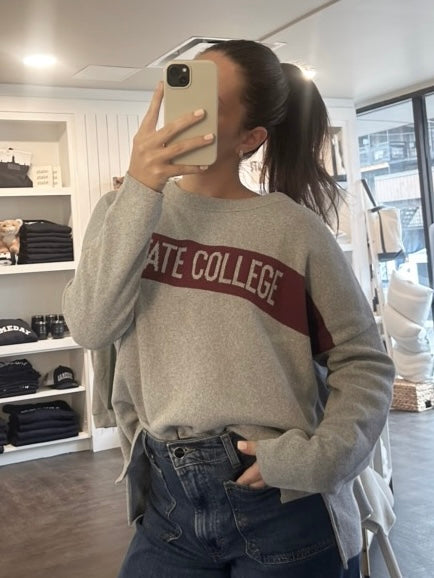 Person wearing a gray sweatshirt with 'STATE COLLEGE' text in a store setting