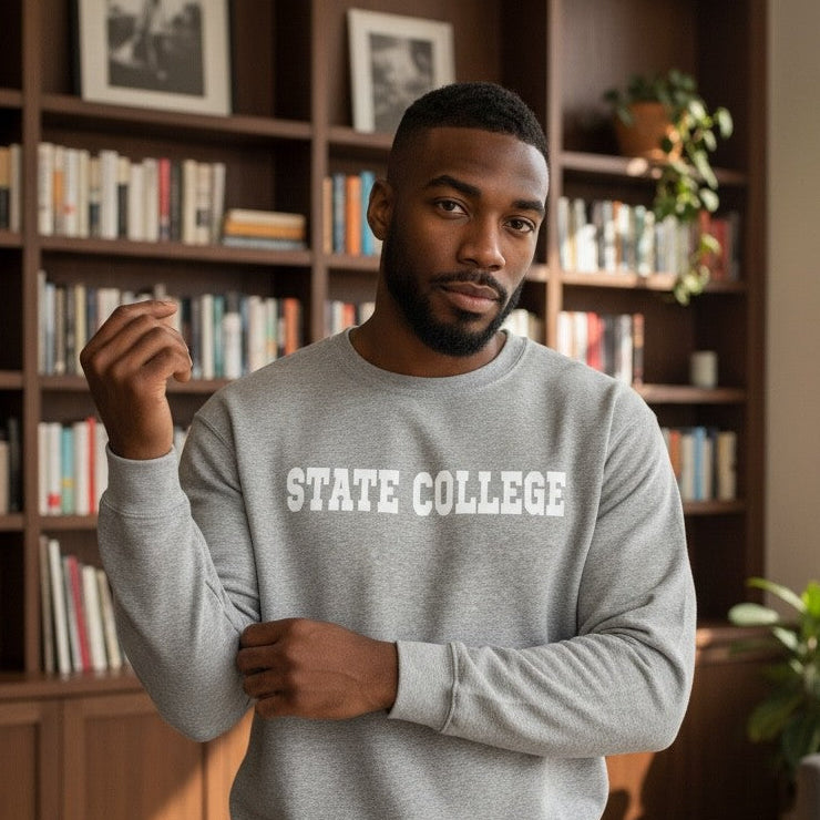 Man wearing a gray sweatshirt with 'STATE COLLEGE' text in a living room.