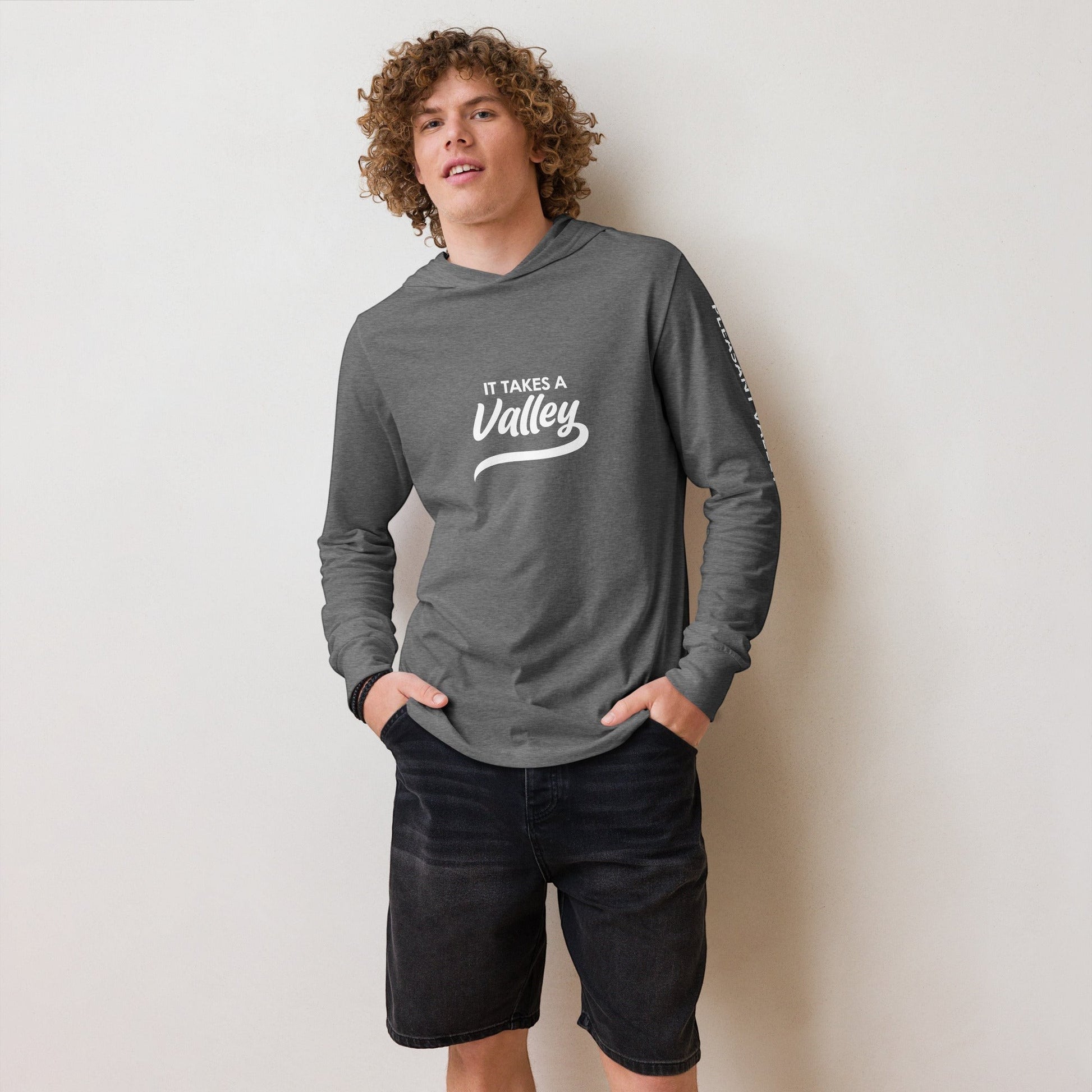 Town Pride State College grey hooded long sleeve tee with It Takes a Valley graphic worn by a curly-haired man