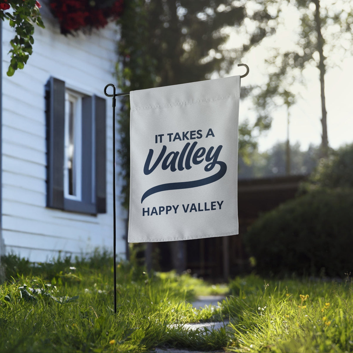 Town Pride State College Happy Valley garden flag made of white polyester with navy blue text displayed in a yard.