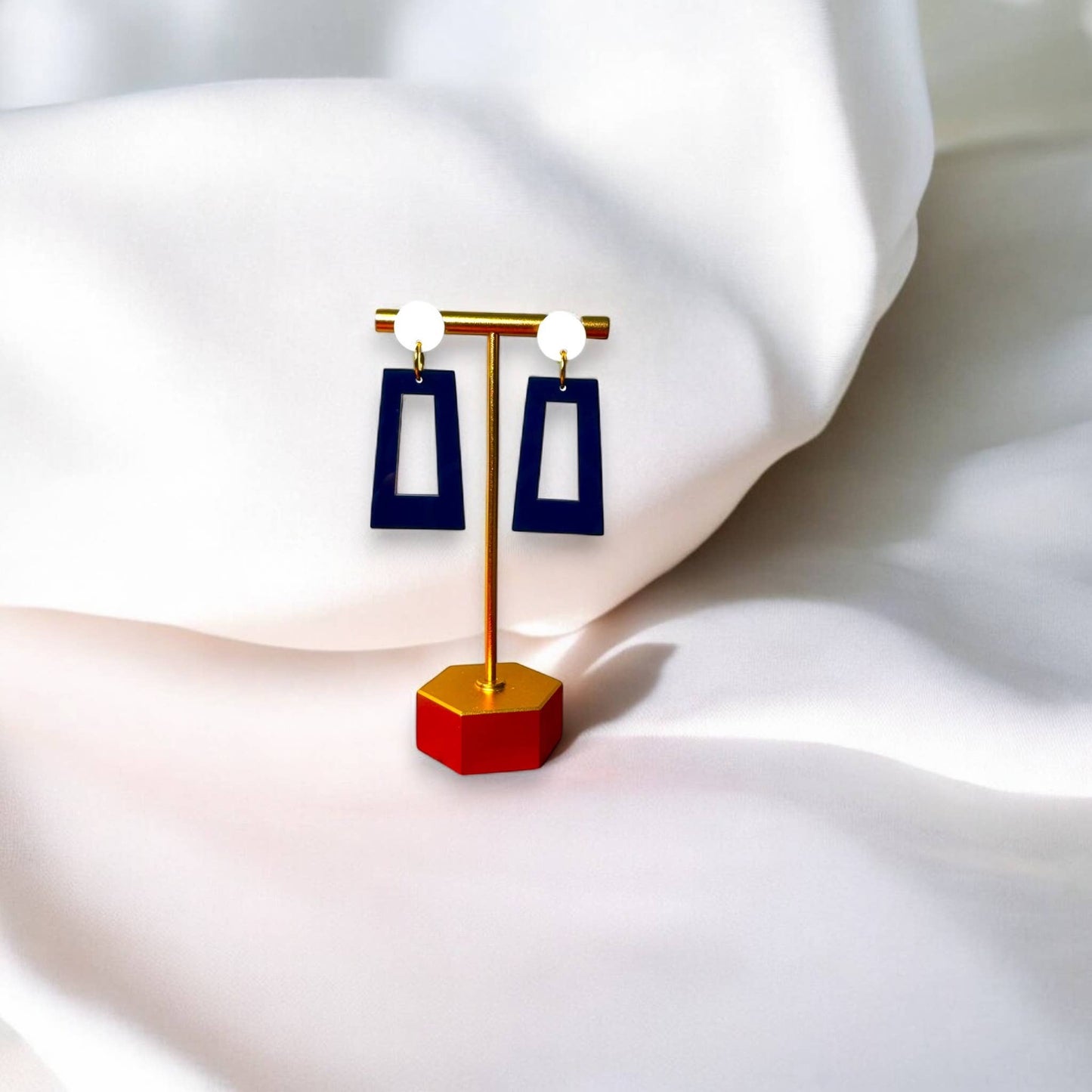 Town Pride State College navy blue acrylic open rectangle earrings with white studs on a gold display stand.