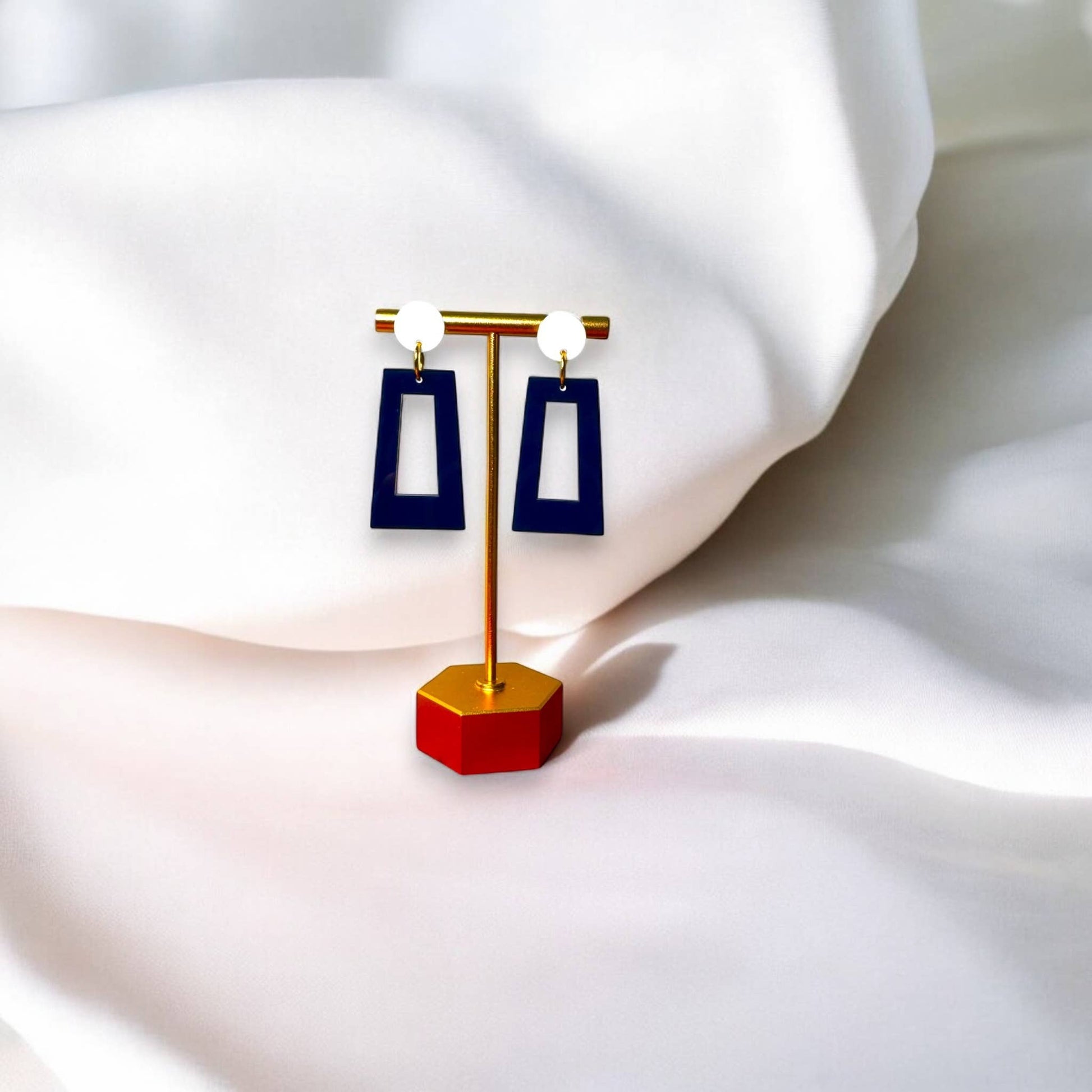 Town Pride State College navy blue acrylic open rectangle earrings with white studs on a gold display stand.