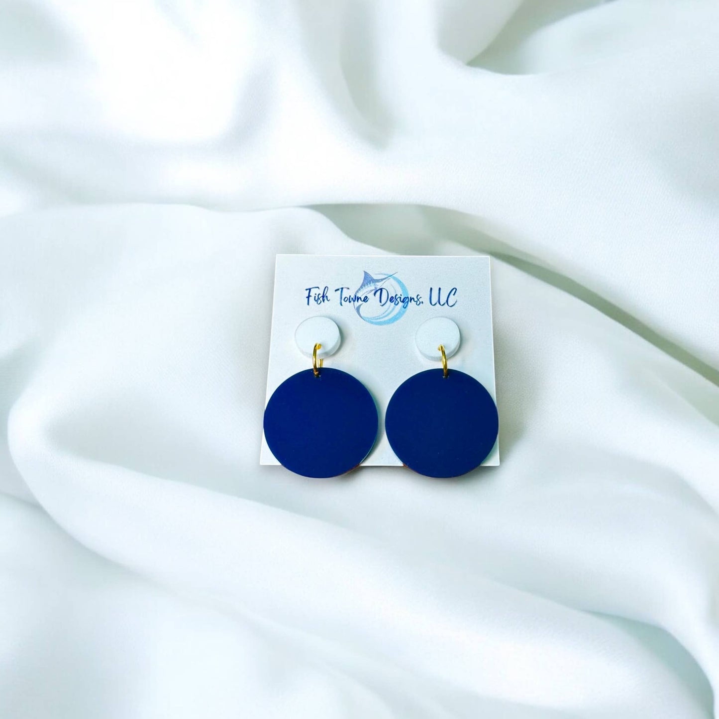Town Pride State College navy blue circle acrylic earrings with white studs on a display card against white fabric.