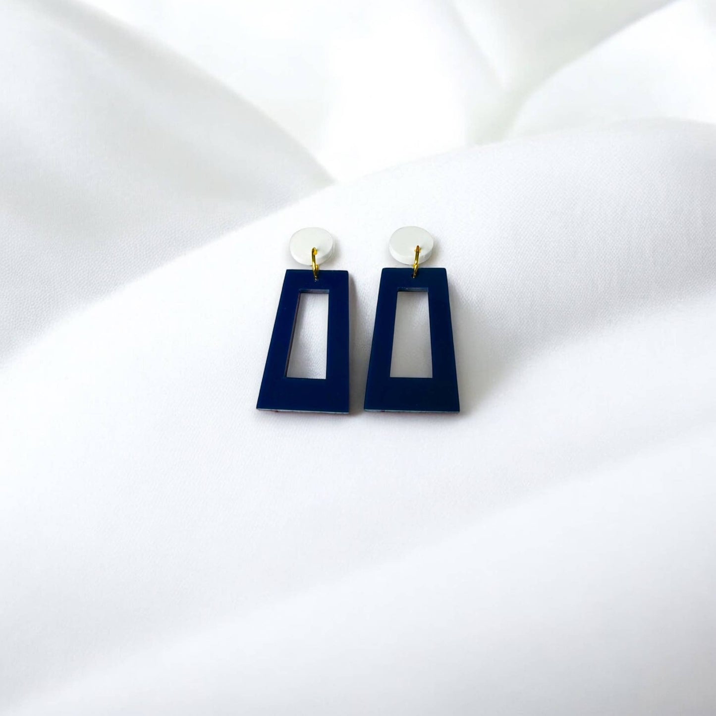 Town Pride State College navy blue acrylic open rectangle earrings with white circular studs on white fabric.
