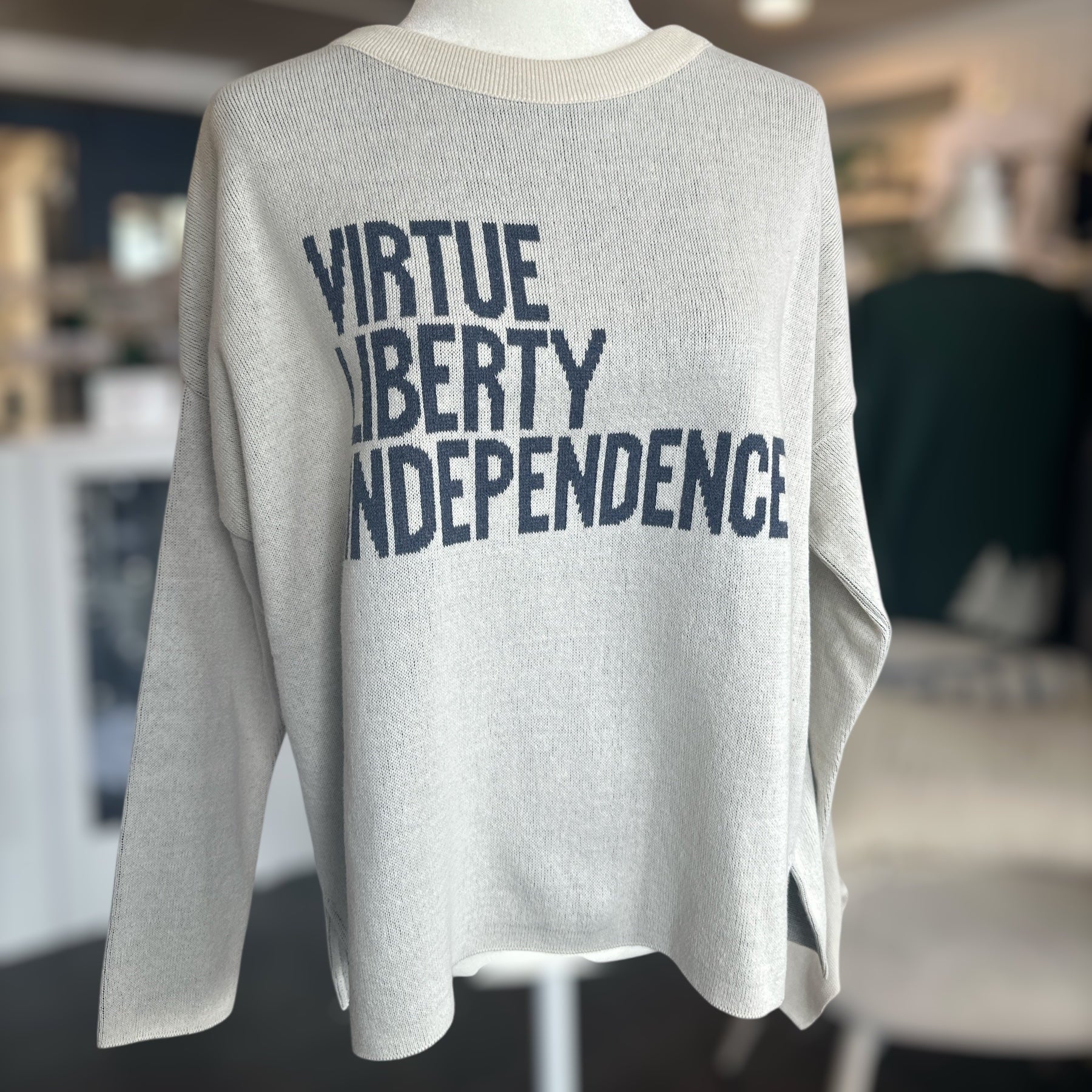 sweater with 'Virtue Liberty Independence' text on a mannequin in an indoor setting.